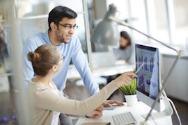 Kollegen sitzen an Computer mit Microsoft Teams Kollegen sitzen im Büro an einem Computer mit Microsoft Teams